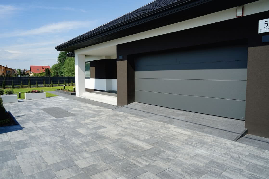 Podjazd wykonany z bruku betonowego w naturalnych odcieniach przypominających kamień Podjazd wykonany z bruku betonowego w naturalnych odcieniach przypominających kamień